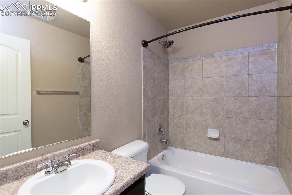 Image 21 of 33: Bathroom featuring bathtub / shower combination, vanity, and a textured wal