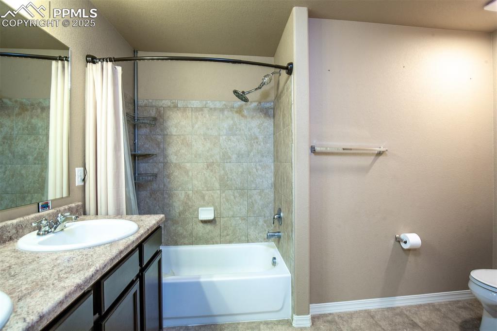 Image 23 of 33: Bathroom featuring shower / bath combo with shower curtain and double vanit