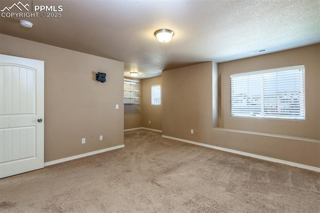 Image 27 of 33: Empty room with a textured ceiling and light colored carpet