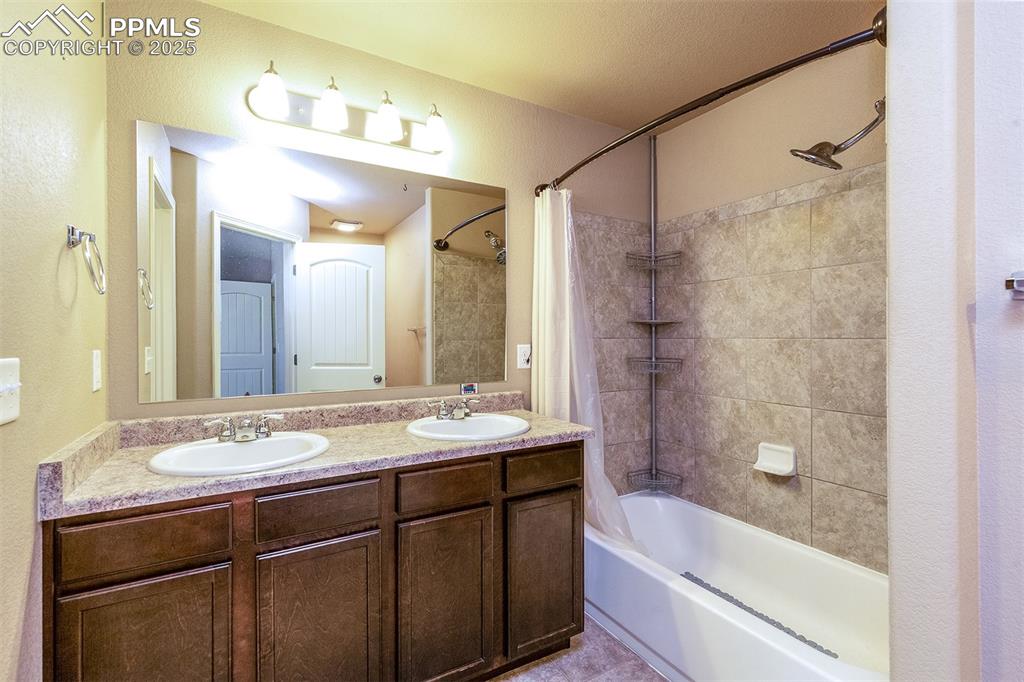 Image 28 of 33: Full bath featuring shower / bathtub combination with curtain, double vanit