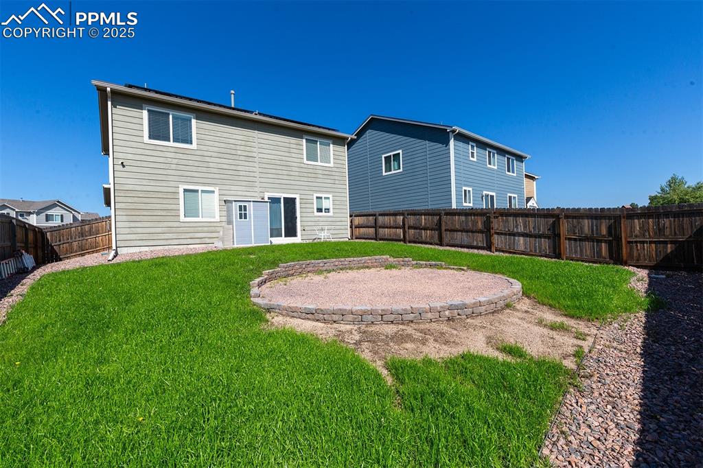 Image 32 of 33: Rear view of house with a fenced backyard