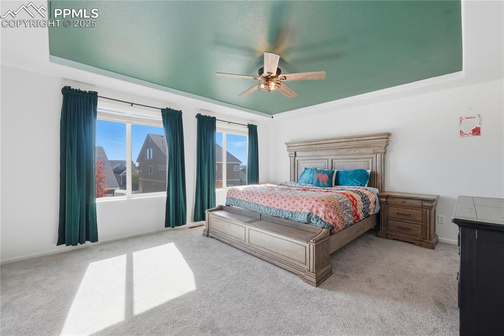 Image 12 of 37: Carpeted bedroom featuring a tray ceiling and ceiling fan