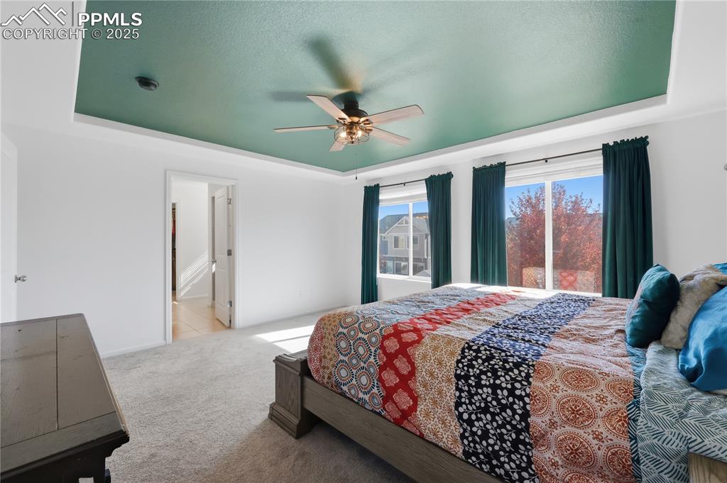 Image 13 of 37: Bedroom featuring a tray ceiling, carpet flooring, a ceiling fan, ensuite b