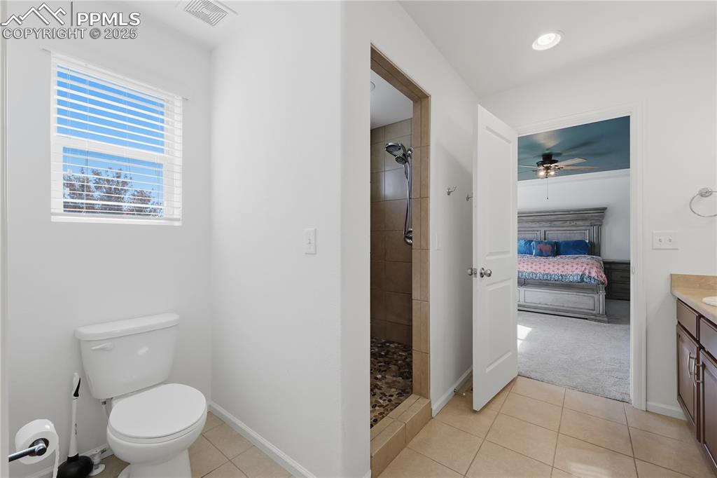 Image 16 of 37: Ensuite bathroom with vanity, light tile patterned floors, tiled shower, ce