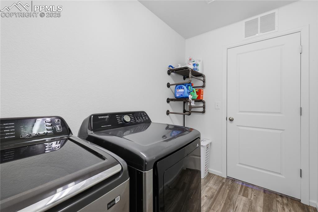 Image 27 of 37: Washroom with wood finished floors and washer and dryer