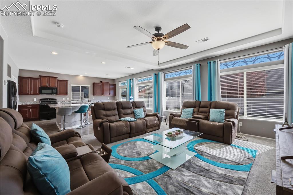 Image 3 of 37: Carpeted living area with a tray ceiling, a ceiling fan, and recessed light