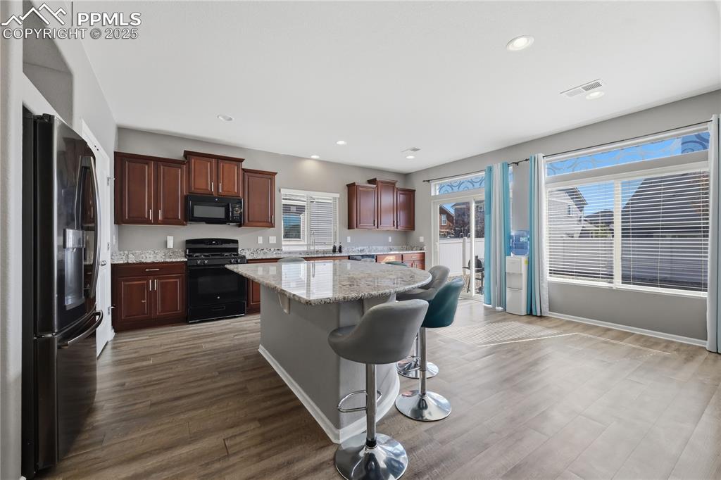 Image 4 of 37: Kitchen featuring black appliances, dark wood-style flooring, a kitchen bar