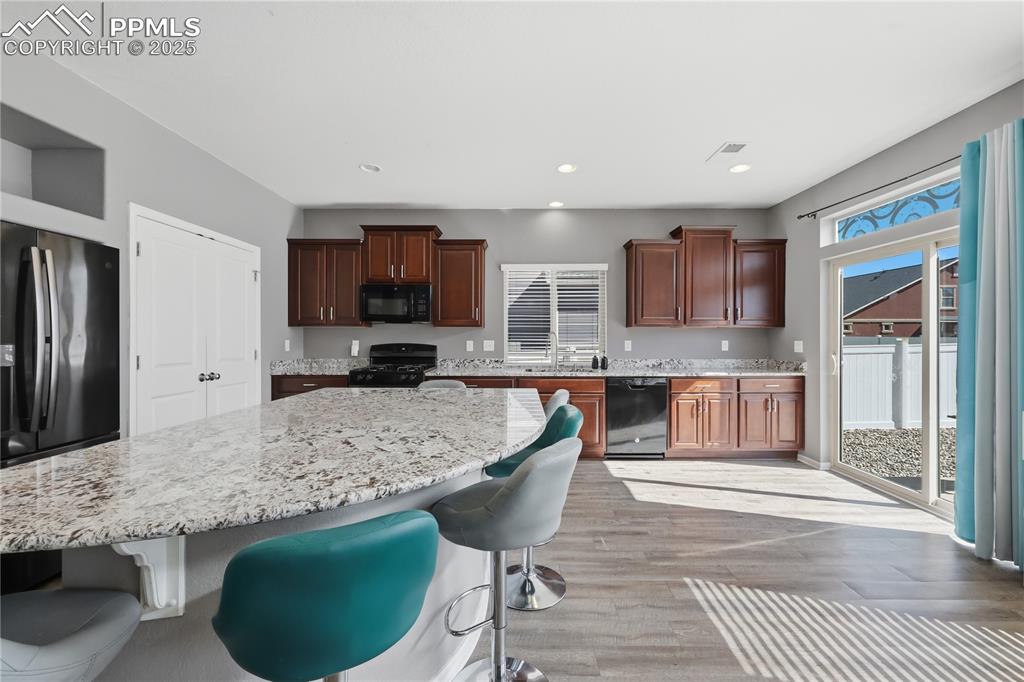 Image 5 of 37: Kitchen with a kitchen breakfast bar, black appliances, light wood-style fl