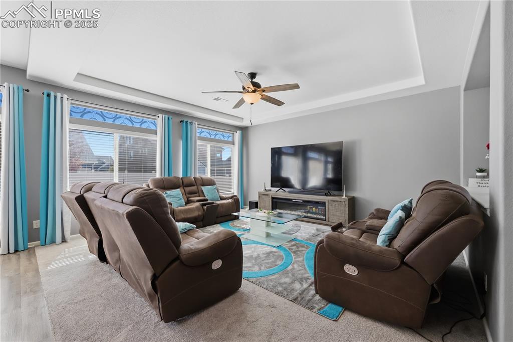 Image 8 of 37: Living area featuring a raised ceiling and a ceiling fan