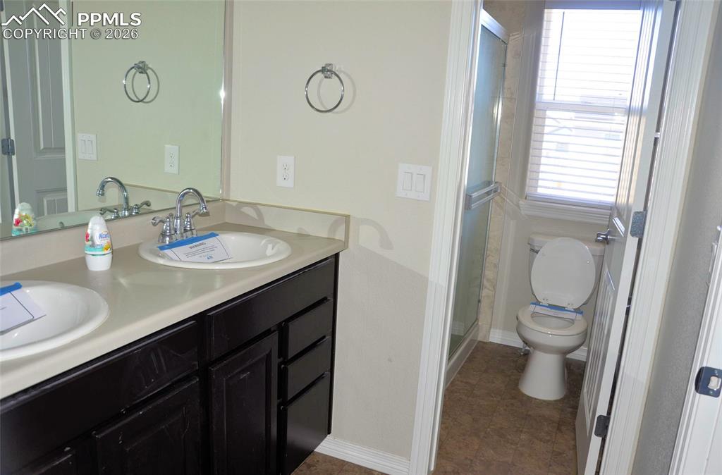 Image 11 of 16: Bathroom featuring double vanity and a shower stall