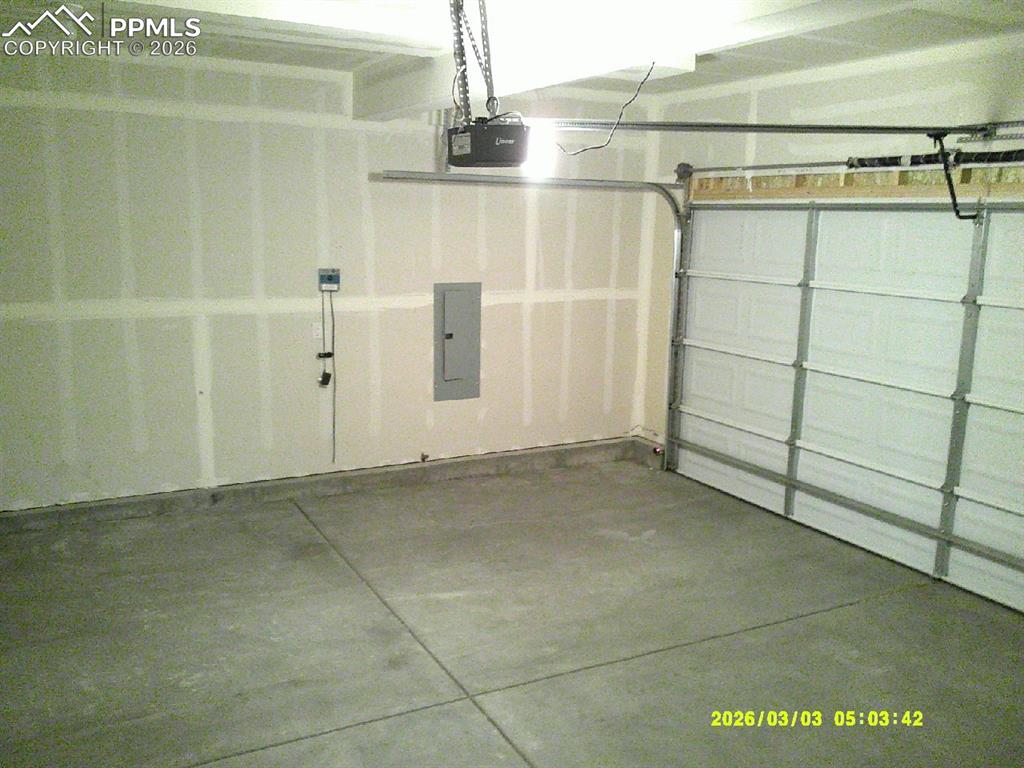 Image 12 of 16: Garage featuring electric panel and a garage door opener