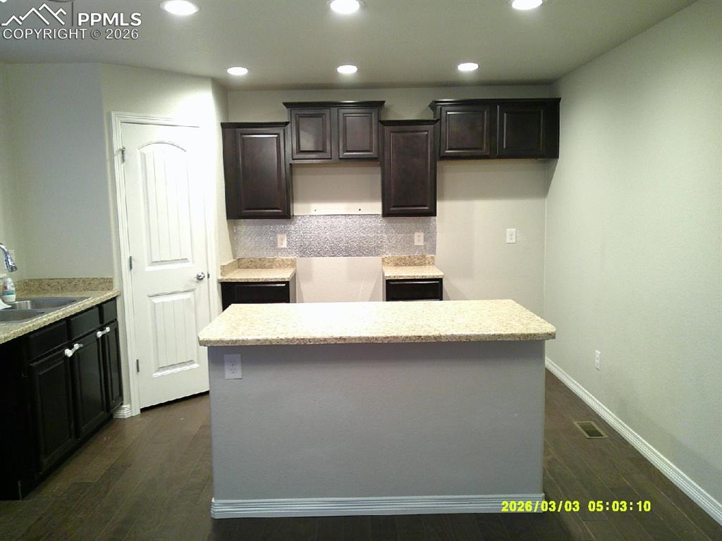 Image 3 of 16: Kitchen featuring a kitchen island, dark wood finish cabinetry, recessed li