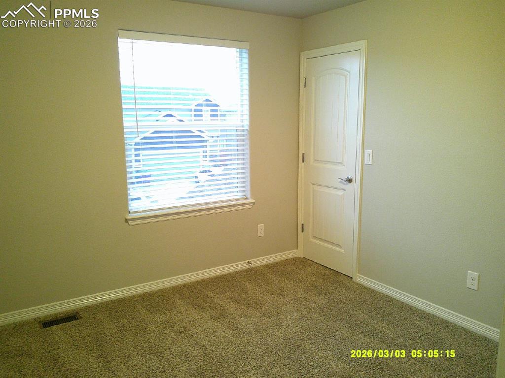 Image 9 of 16: Empty room featuring dark colored carpet and baseboards