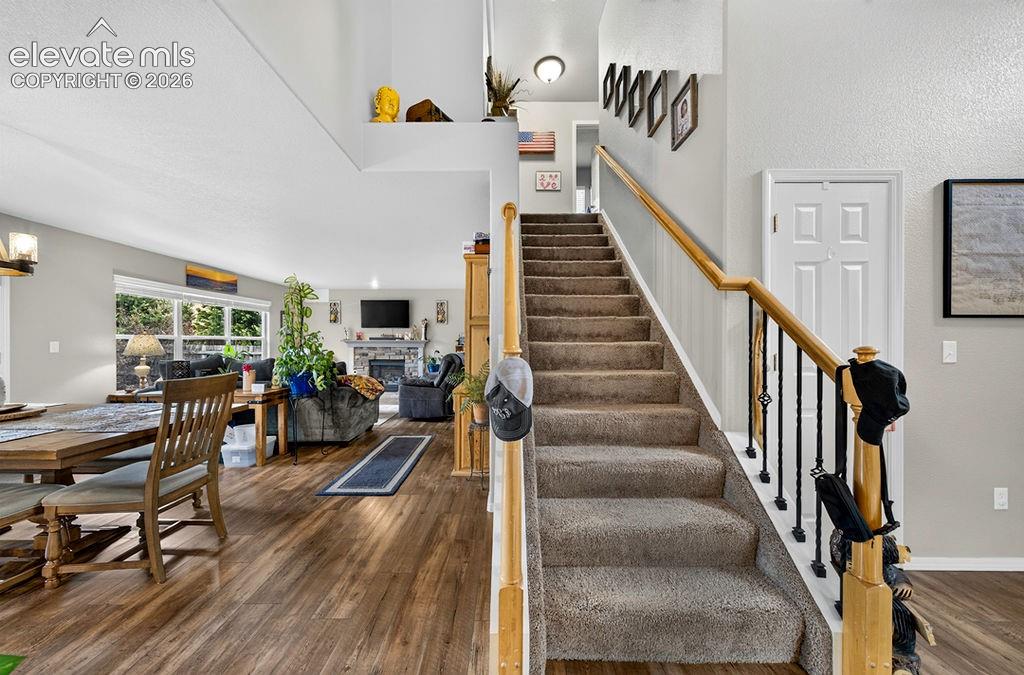 Image 20 of 44: Stairs to the upper level with iron rails and neutral carpet.