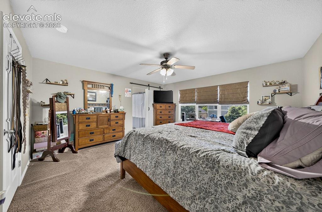 Image 22 of 44: Upper level Primary Bedroom with custom barn door into the adjoining Primar