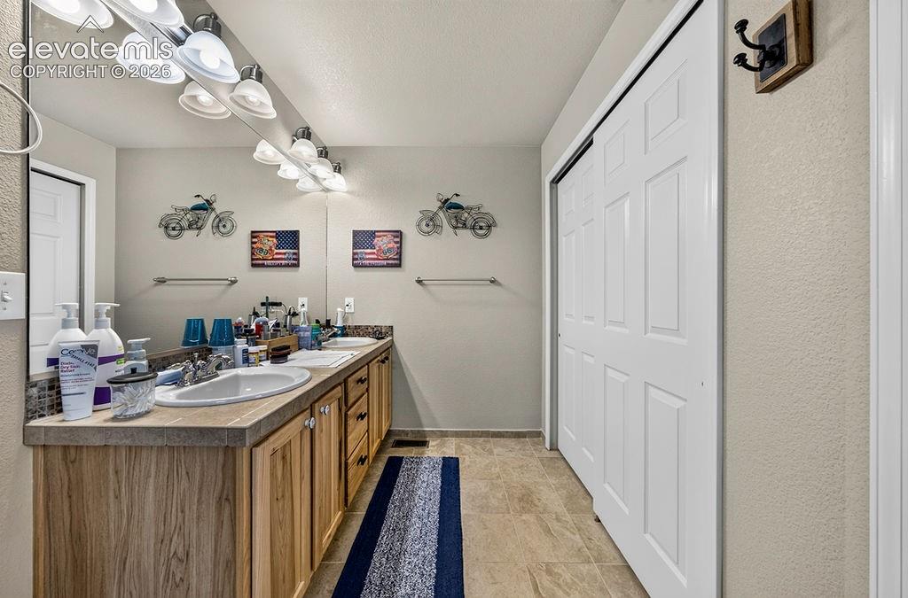 Image 24 of 44: Beautiful upper level Primary Bathroom with a tile floor, hickory dual sink