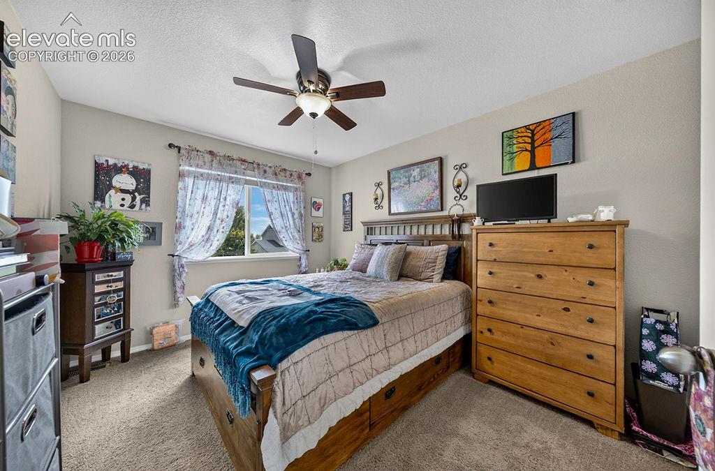 Image 26 of 44: Upper Level Bedroom #2 has neutral carpet and a lighted ceiling fan.