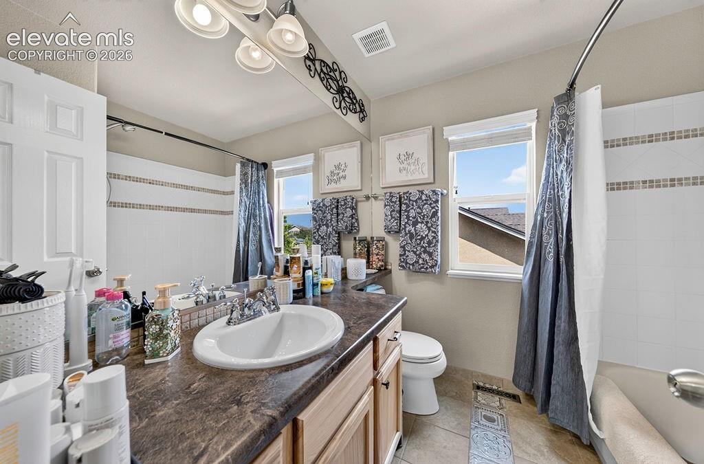 Image 31 of 44: Upper Level Full Bathroom with tile flooring, a vanity, mirror, and tiled t