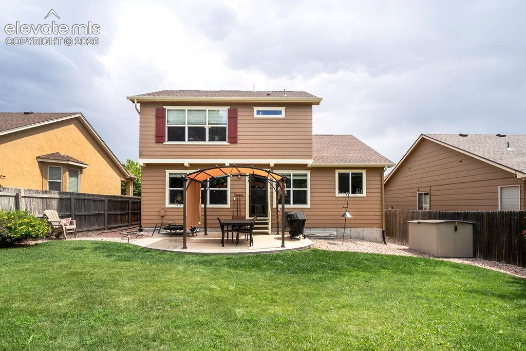 Image 42 of 44: Rear view of home and backyard patio with covered pergola.
