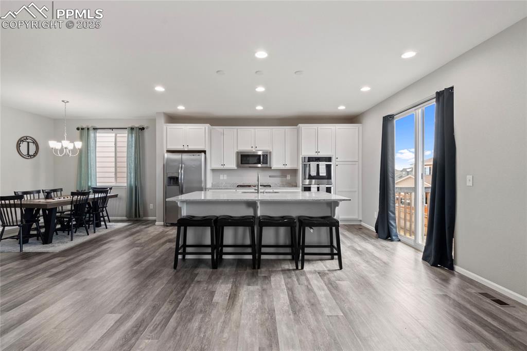 Image 10 of 44: Kitchen featuring white cabinetry, an island with sink, stainless steel app