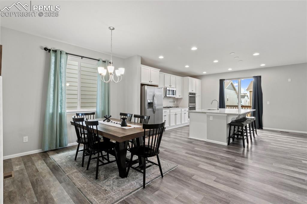 Image 12 of 44: Dining room with a chandelier, light wood finished floors, and recessed lig