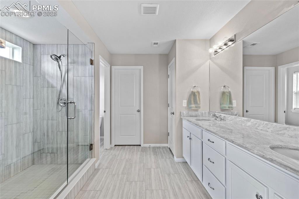Image 21 of 44: Bathroom with a shower stall and double vanity