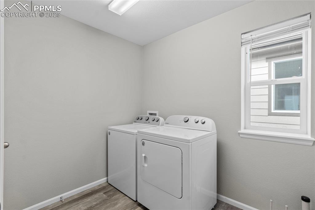 Image 28 of 44: Laundry area with wood finished floors and independent washer and dryer