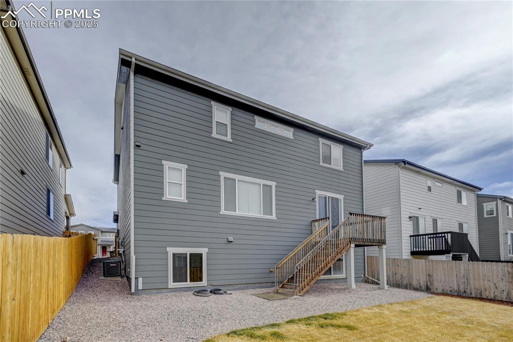 Image 34 of 44: Rear view of house featuring stairs, a fenced backyard, and a deck