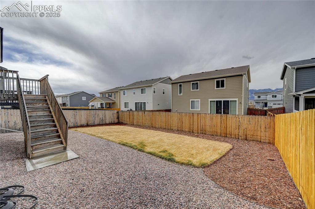 Image 35 of 44: Fenced backyard with a residential view, a deck, and stairway