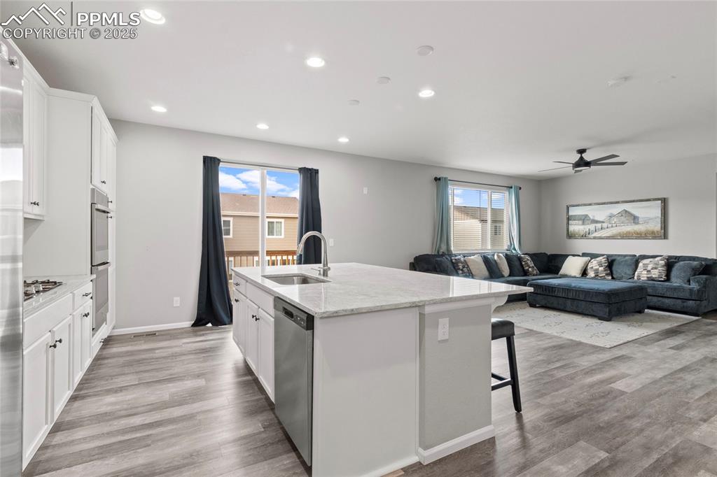 Image 4 of 44: Kitchen featuring white cabinets, open floor plan, a breakfast bar, an isla