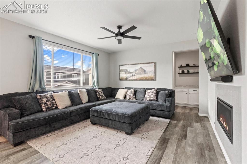 Image 5 of 44: Living room featuring wood finished floors, a tiled fireplace, and a ceilin