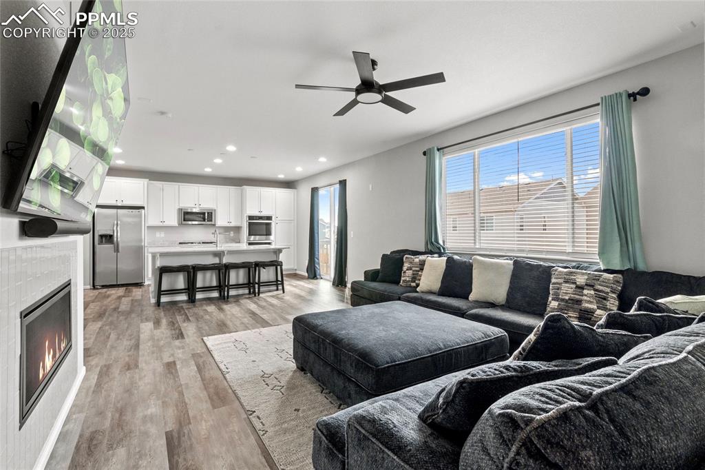 Image 6 of 44: Living area featuring a tile fireplace, light wood-style floors, recessed l