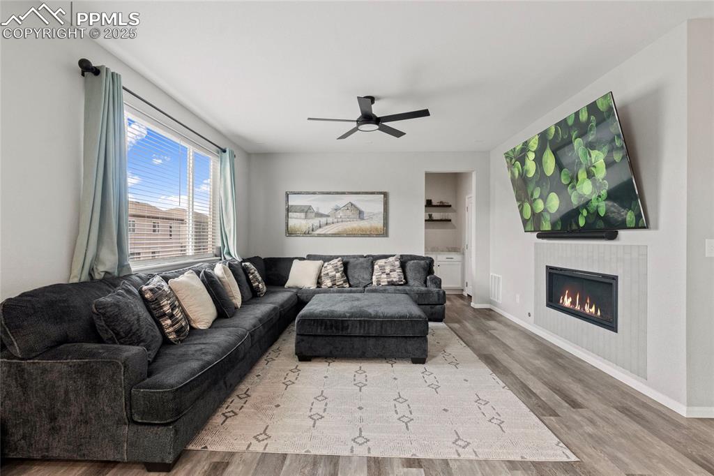 Image 8 of 44: Living area featuring wood finished floors, a glass covered fireplace, and