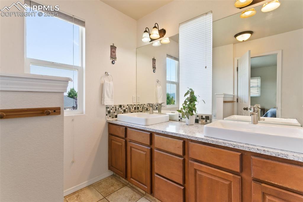 Image 16 of 29: Ensuite bathroom featuring double vanity, light tile flooring