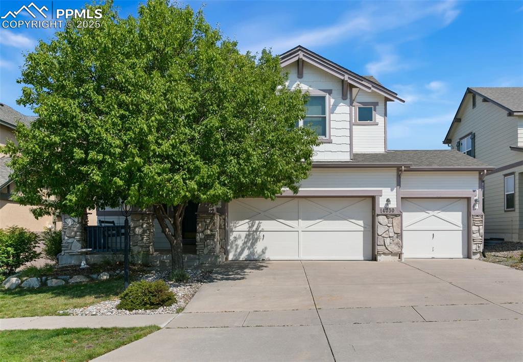 Image 2 of 29: View of property featuring spacious 3 car garage and front lawn with shade