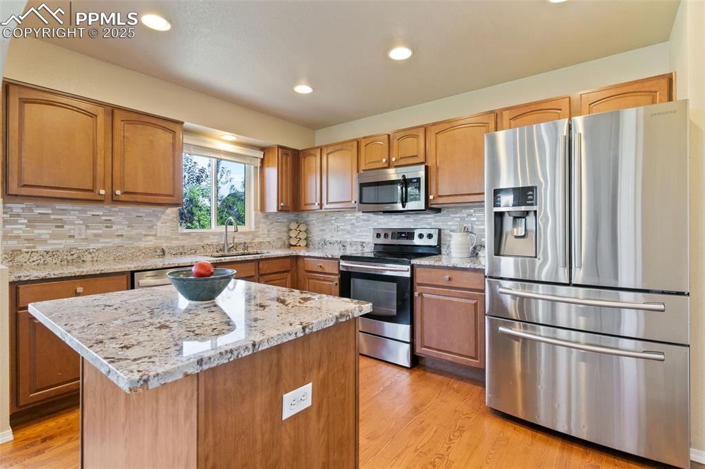 Image 6 of 29: Kitchen featuring appliances with stainless steel finishes, light stone cou