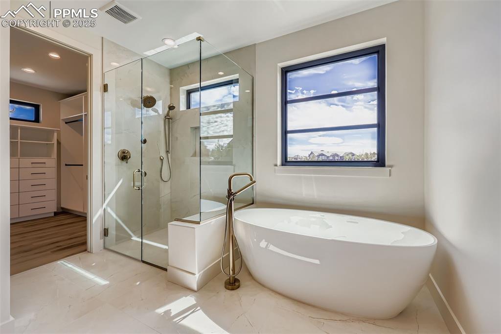 Image 15 of 41: Bathroom featuring a freestanding bath, a marble finish shower, marble fini