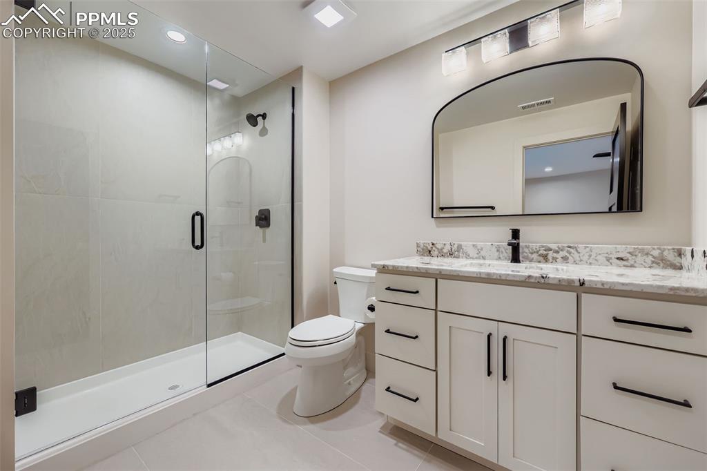 Image 19 of 41: Bathroom with vanity, a shower stall, light tile patterned floors, and rece