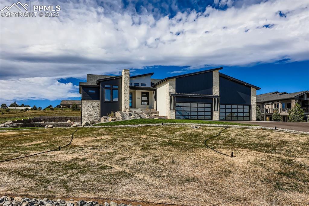 Image 4 of 41: View of front of home with stone siding, a garage, driveway, and a front ya