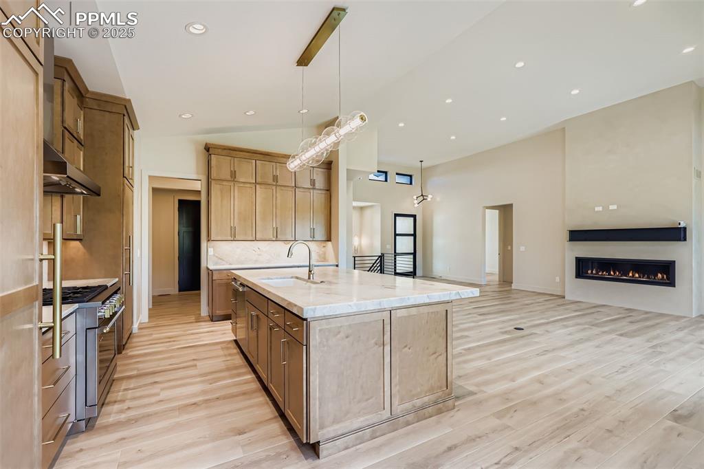 Image 8 of 41: Kitchen with tasteful backsplash, open floor plan, light stone counters, re