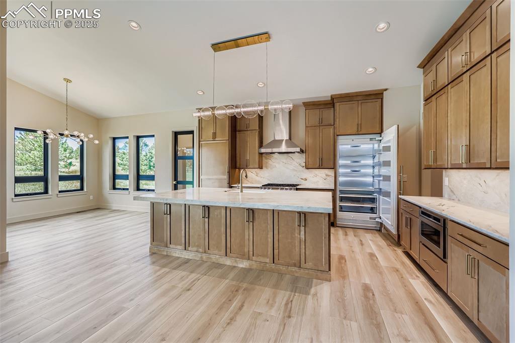 Image 9 of 41: Kitchen with light stone counters, a kitchen island with sink, decorative b
