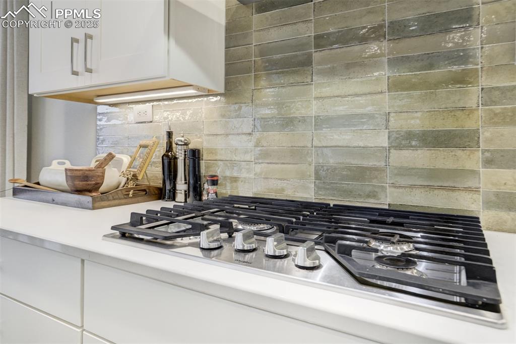 Image 8 of 50: Gas cook top and custom backsplash