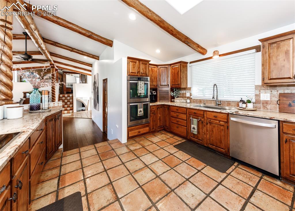 Image 14 of 50: Kitchen with backsplash, light stone counters, stainless steel appliances, 