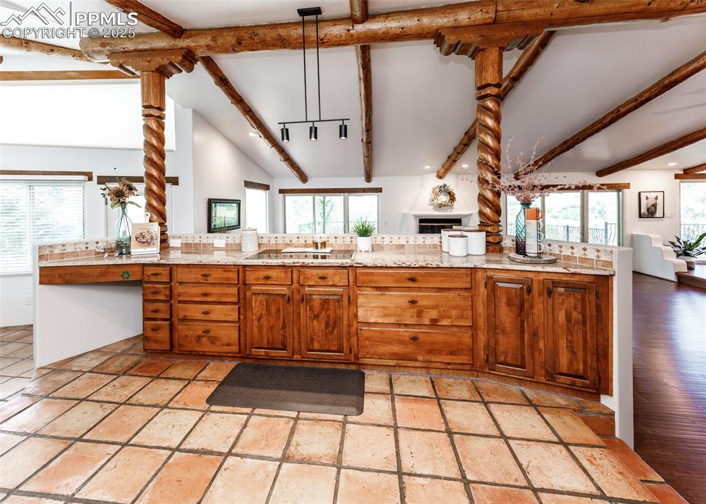 Image 17 of 50: Kitchen featuring brown cabinets, open floor plan, decorative light fixture