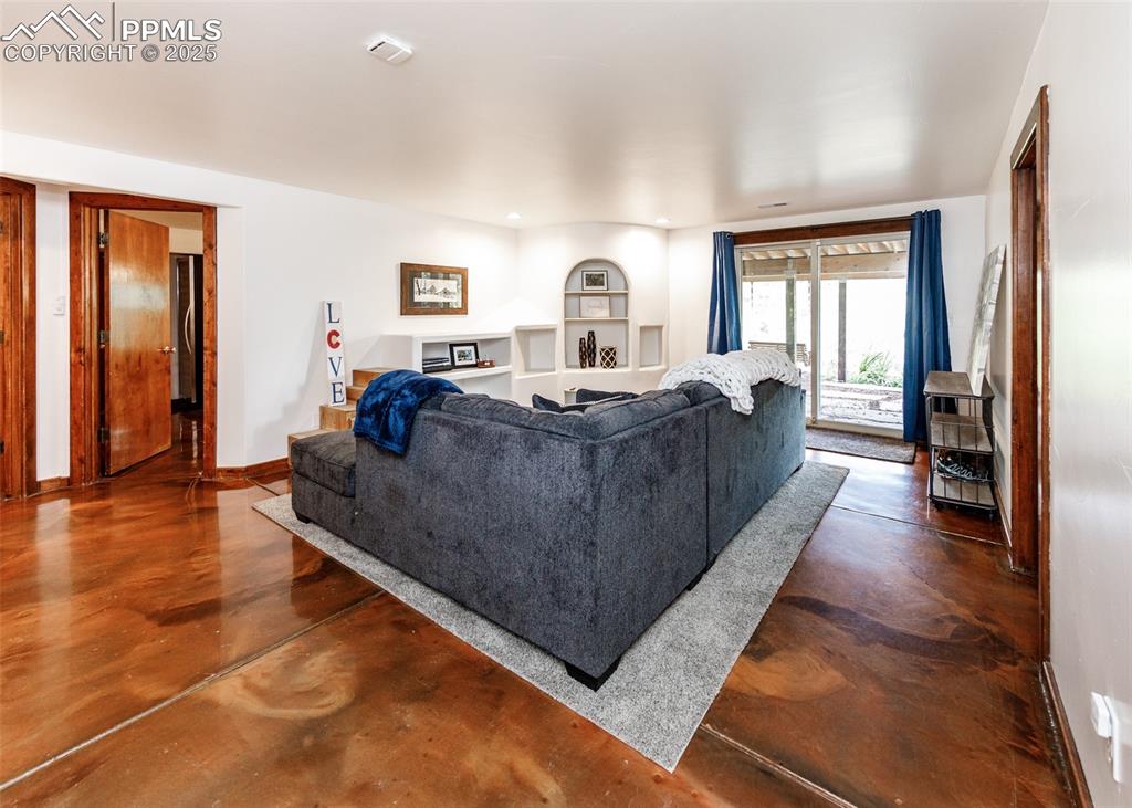 Image 31 of 50: Living room with finished concrete floors and built in features