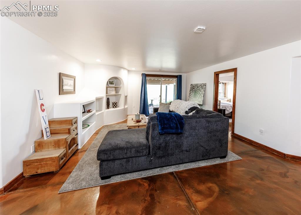 Image 32 of 50: Living room with concrete floors and built in shelves