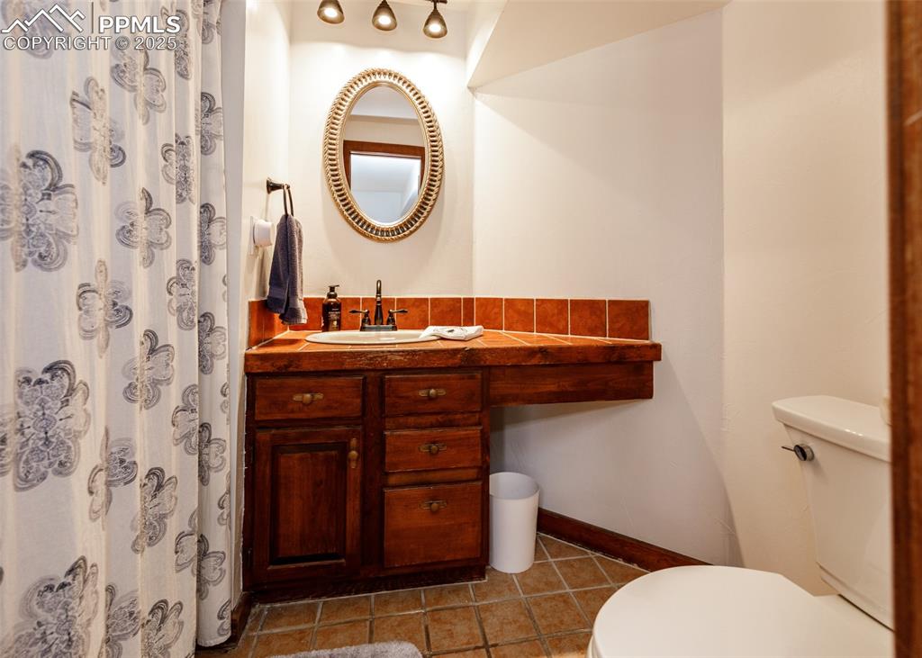 Image 35 of 50: Bathroom with tile patterned flooring, vanity, and a shower with curtain
