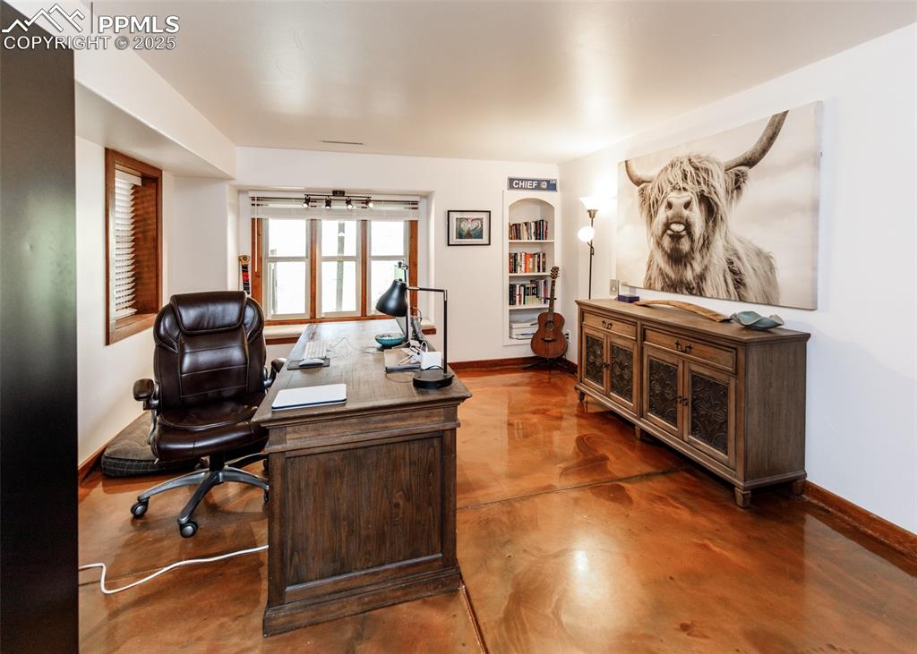 Image 38 of 50: Home office with concrete floors and baseboards