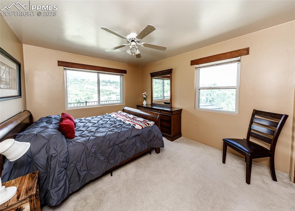 Image 41 of 50: Bedroom featuring light colored carpet, multiple windows, and ceiling fan