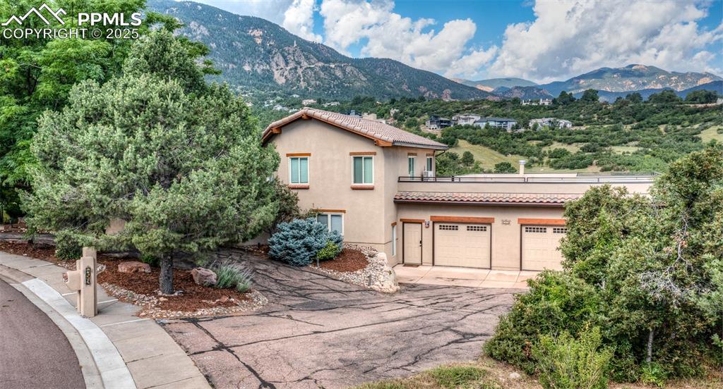 Image 43 of 50: View of front of home with stucco siding, a mountain view, driveway, and a 
